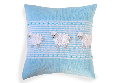 A square light blue knit throw pillow featuring three white and gray knitted sheep appliqués across a horizontal band of white stripes.